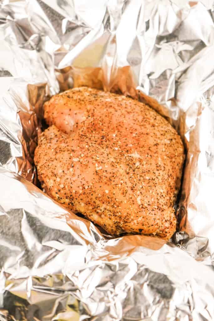 Seasoned turkey breast in a foil boat ready for the smoker