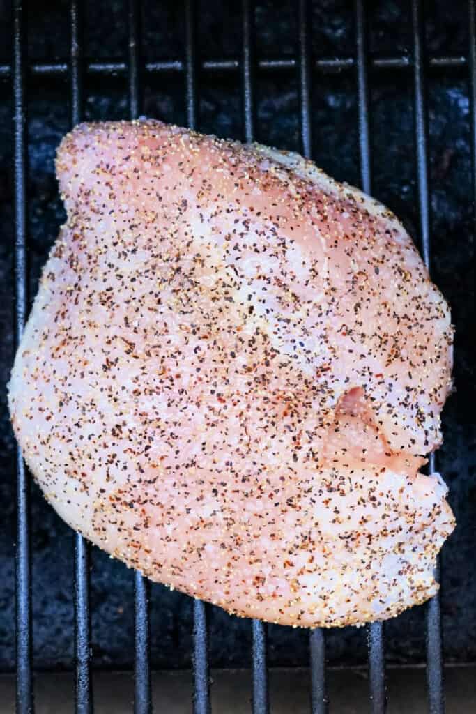 Raw seasoned turkey breast placed directly on a smoker grate