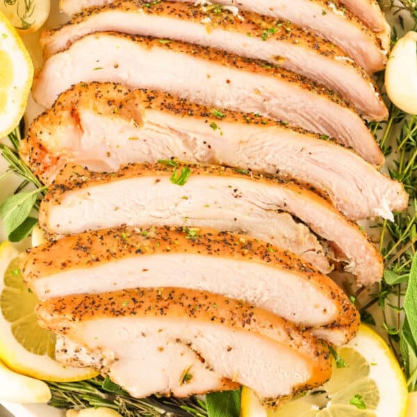 Square image of sliced smoked garlic herb turkey breast with lemon and herbs