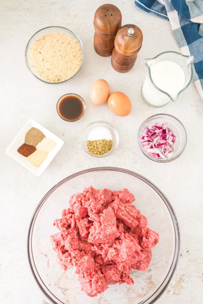 Ingredients for smoked meatloaf laid out, including ground beef, spices, eggs, milk, and breadcrumbs