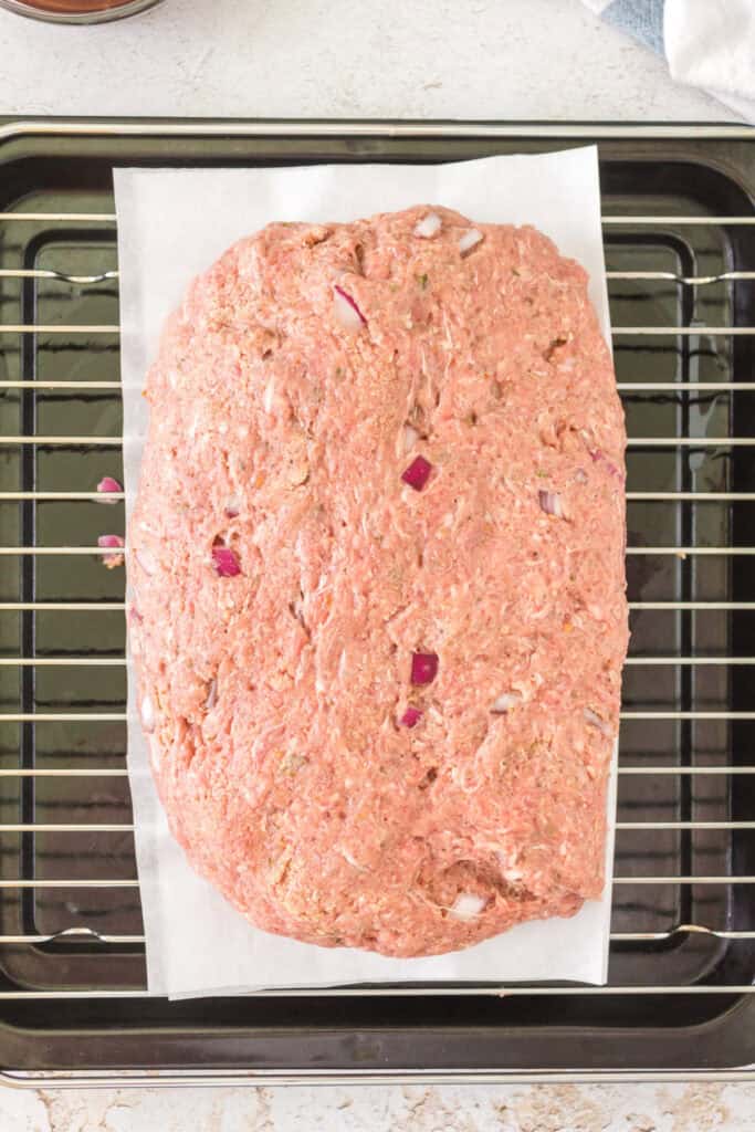 	Uncooked meatloaf shaped and placed on parchment over a wire rack