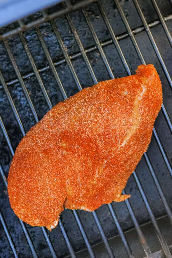 Raw seasoned turkey breast on the smoker grates