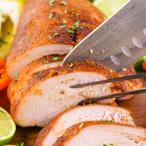 Close-up of smoked turkey breast being sliced with knife and fork