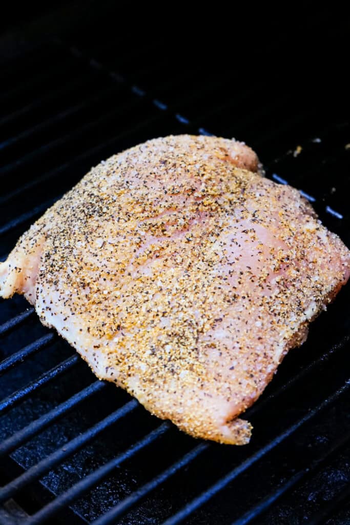 Seasoned raw turkey breast placed directly on a smoker grill grate