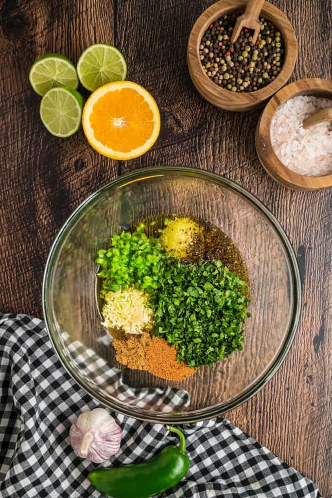Marinade ingredients in a glass bowl including cilantro, garlic, and jalapeño