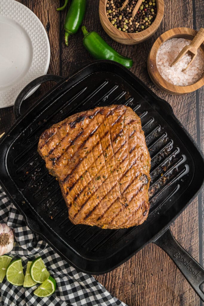 Grilled flank steak cooking in a cast iron grill pan