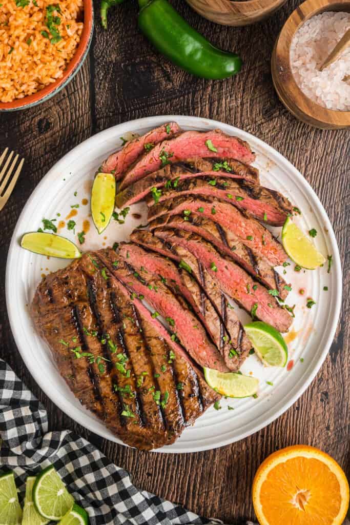 Overhead view of a platter with sliced carne asada and sides