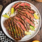 Square image of carne asada slices arranged with limes and cilantro