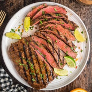 Square image of carne asada slices arranged with limes and cilantro