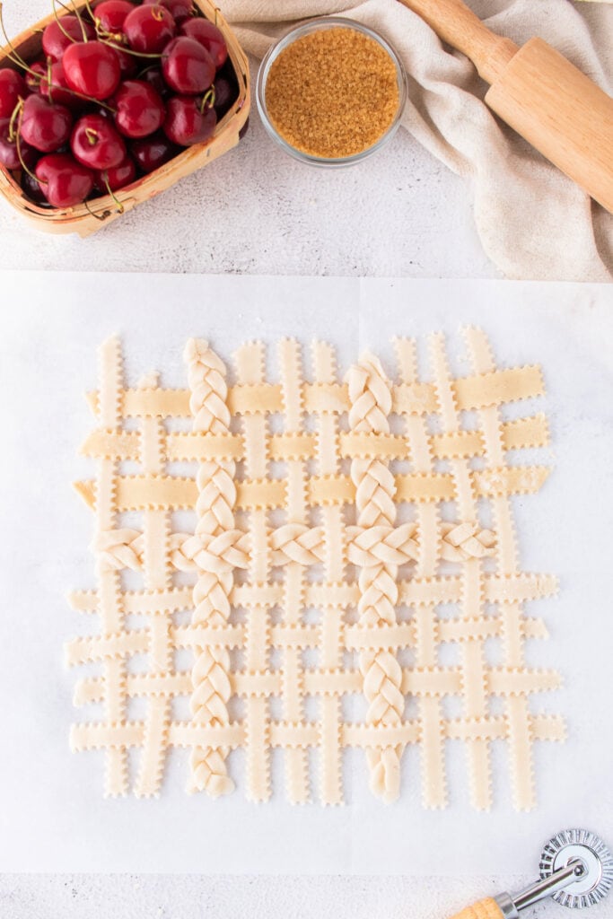 Fully assembled unbaked lattice crust laid out on parchment before topping cherry filling