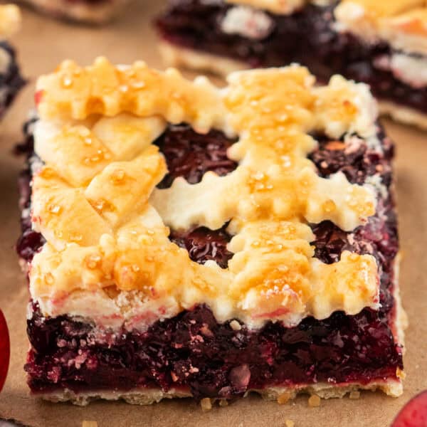 Close-up of a single cherry pie bar square with a crimped lattice crust and golden sugar topping