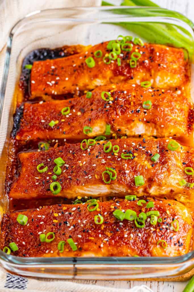 Firecracker salmon garnished with scallions and sesame seeds in a baking dish.