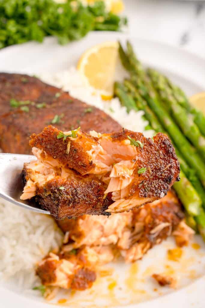Forkful of flaky blackened salmon showing tender inside texture.