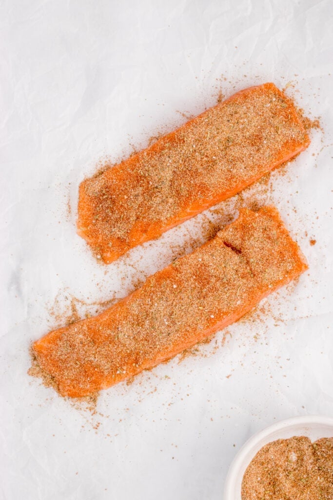 Salmon fillets coated with blackened seasoning before cooking.