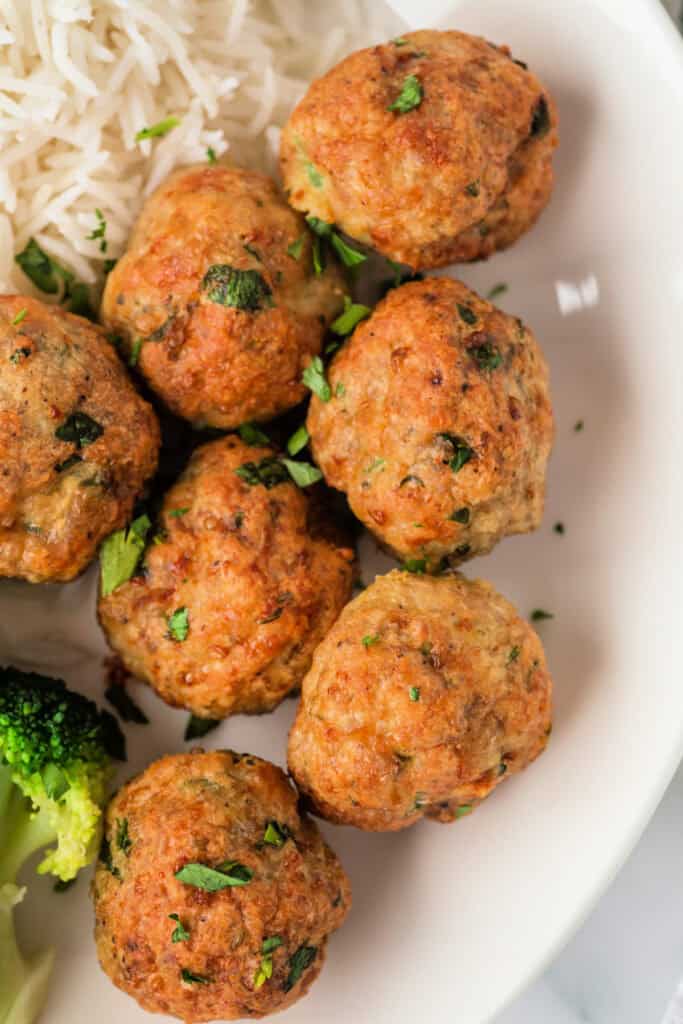 Close-up view of air fried chicken meatballs served with steamed broccoli and white rice
