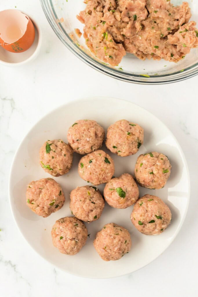 Plate with uncooked chicken meatballs shaped and ready to be placed in the air fryer basket