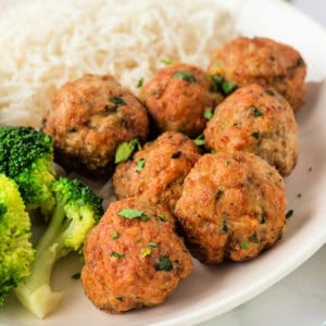 Square crop of golden brown air fryer chicken meatballs served with broccoli and rice