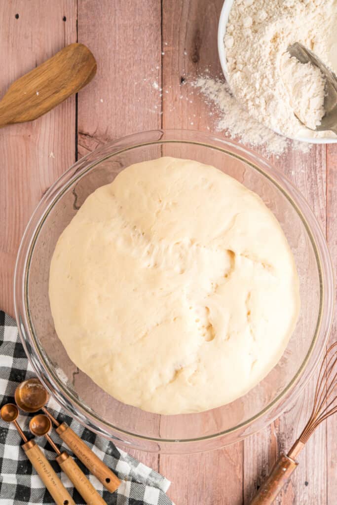 Dough after rising, now doubled in size and filling the glass bowl.