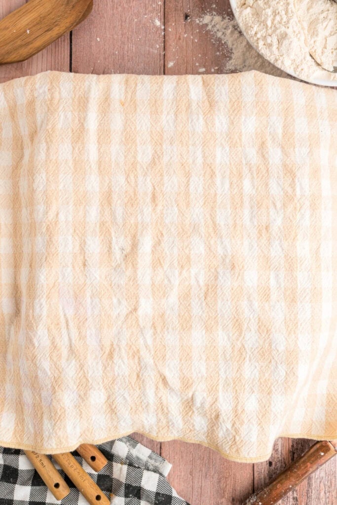 Loaf pans covered with a kitchen towel while the dough rises for the second time.