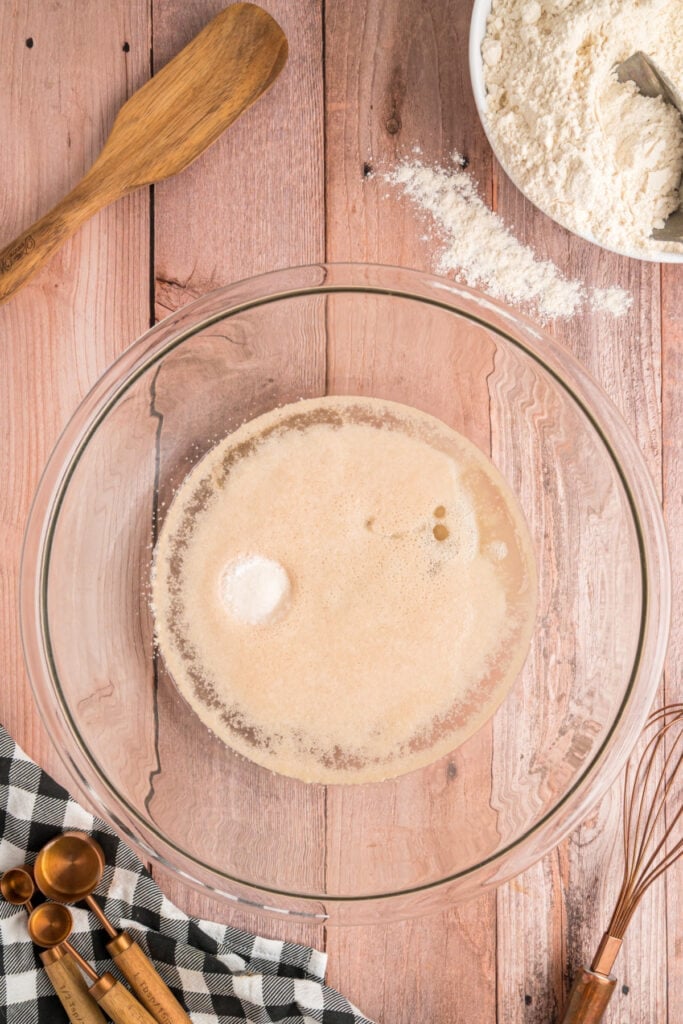 Active yeast mixture with salt and oil added in a glass bowl before mixing in the flour.