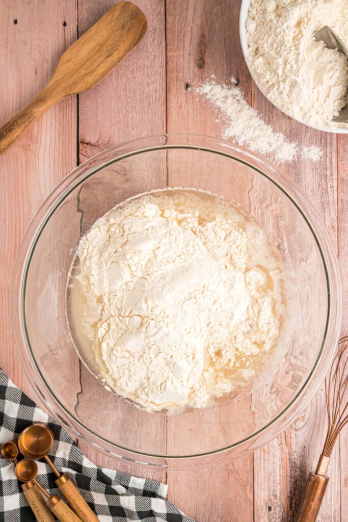 First addition of flour to the yeast mixture in a glass bowl, starting to form the dough.