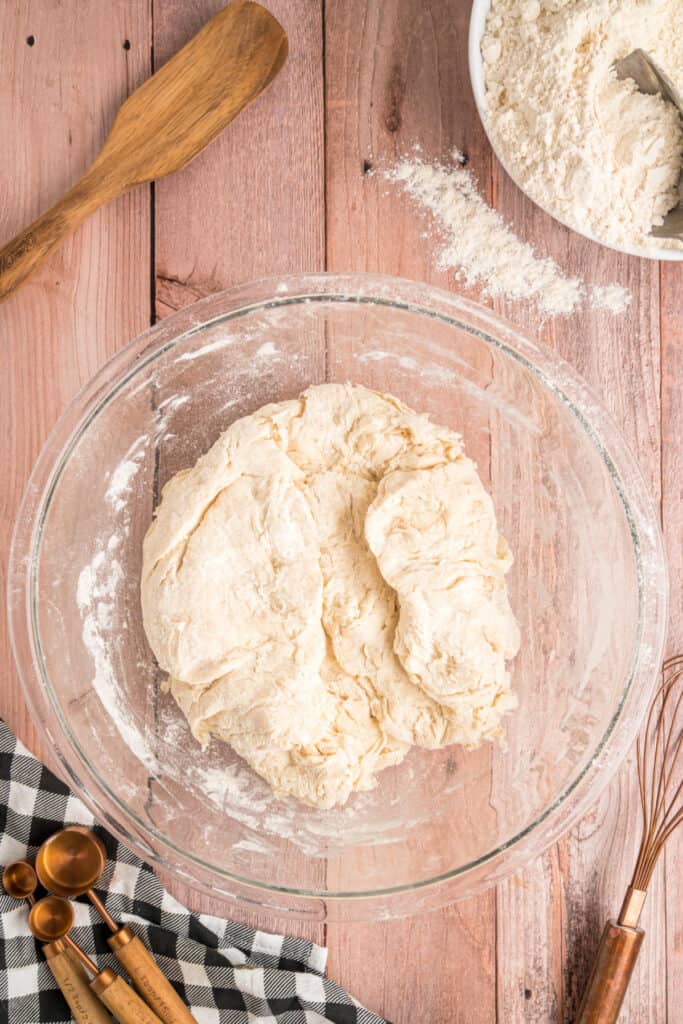 Rough dough fully mixed and ready for kneading, resting in a glass mixing bowl.