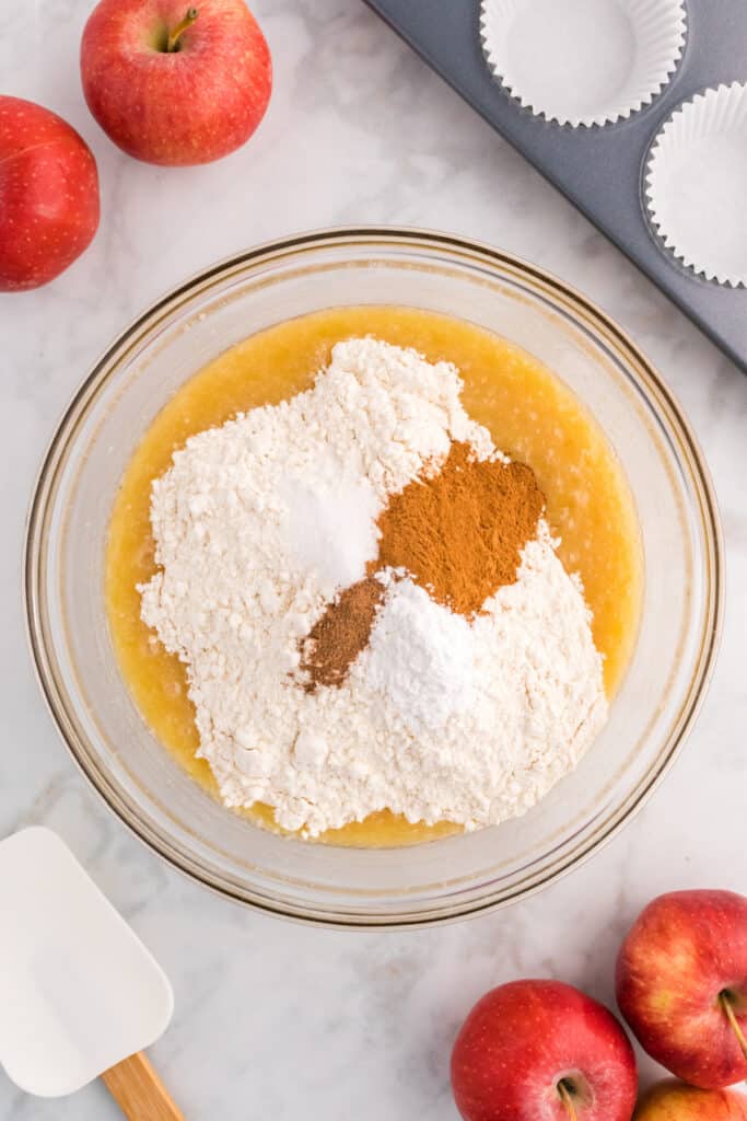 Mixing bowl filled with flour, baking powder, cinnamon, nutmeg, and salt added to the wet mixture.