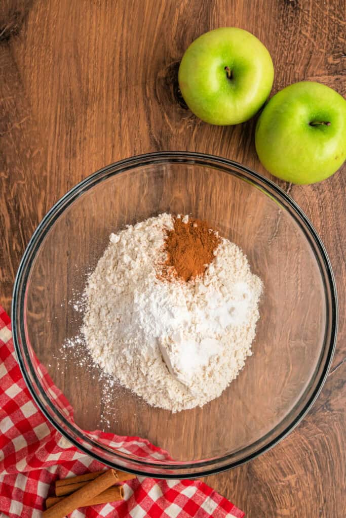 Mixing bowl with flour, cinnamon, baking powder, and baking soda ready to be combined.