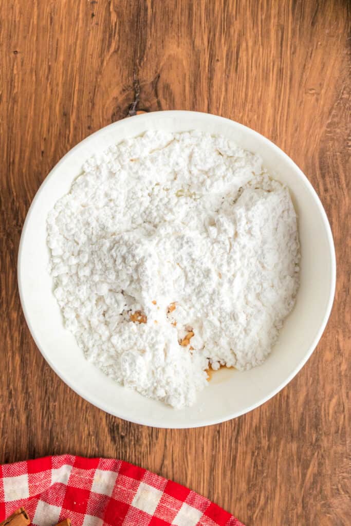 White mixing bowl filled with powdered sugar ready to be whisked into glaze for apple fritter bread.