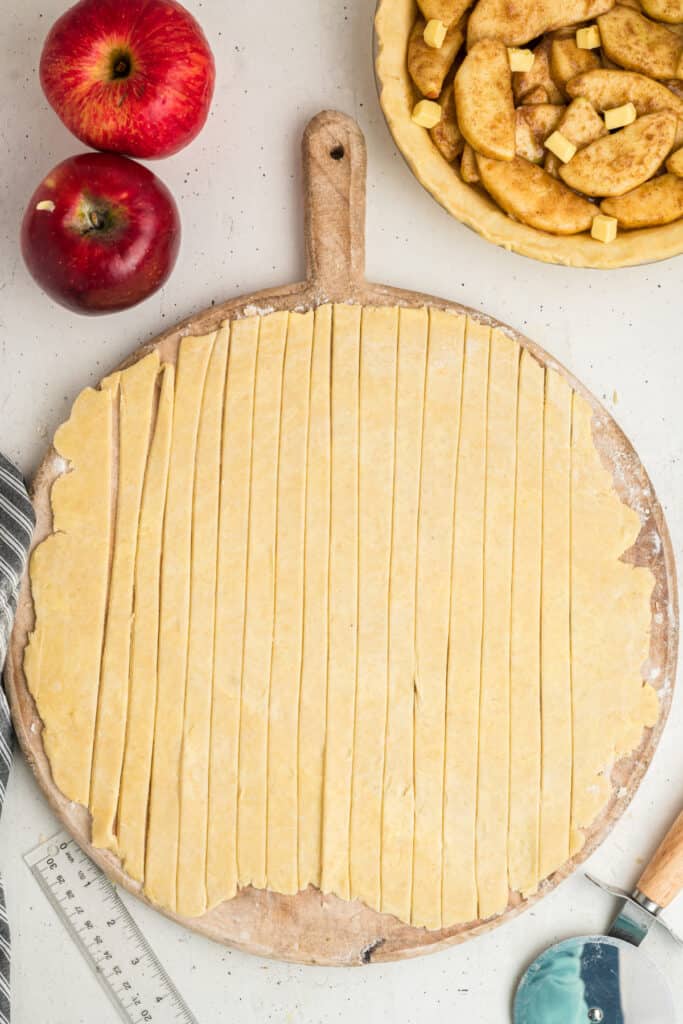 Strips of pie dough cut and laid out on a wooden board for lattice top.