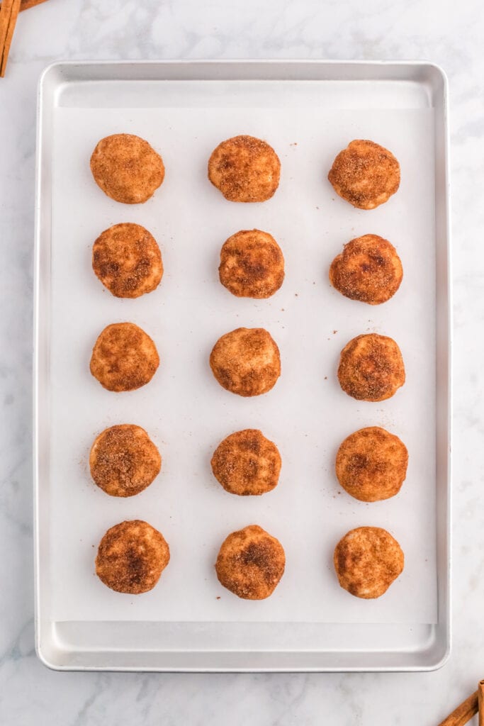 Unbaked apple pie bombs arranged on a parchment-lined baking sheet.
