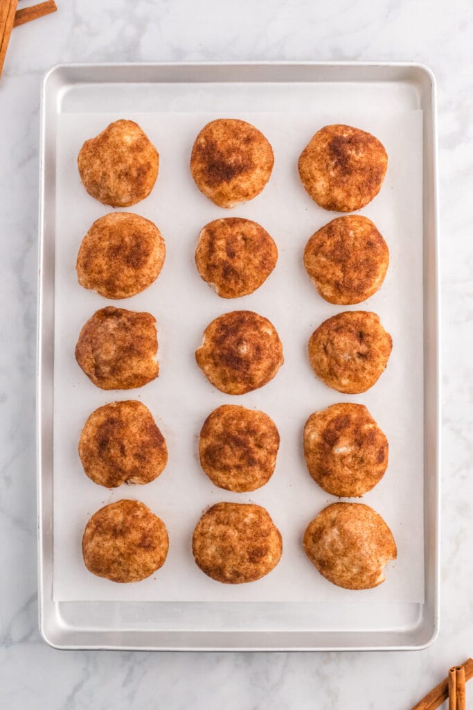 Cinnamon sugar-coated apple pie bombs on a baking sheet after baking.