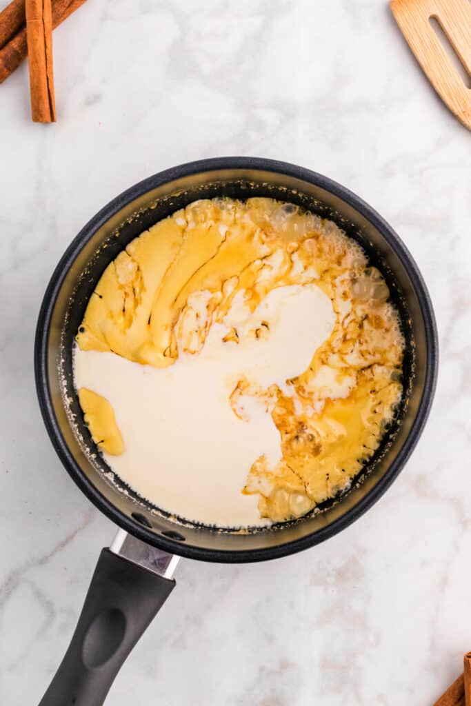 Heavy cream being added to caramelized sugar mixture while making spiced caramel sauce.