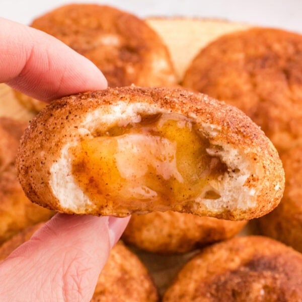 Square image of an apple pie bomb with gooey spiced apple filling inside, held up to show the center.