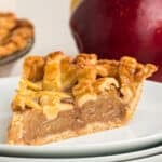 Close-up square photo of apple pie slice showing flaky crust and apple filling.