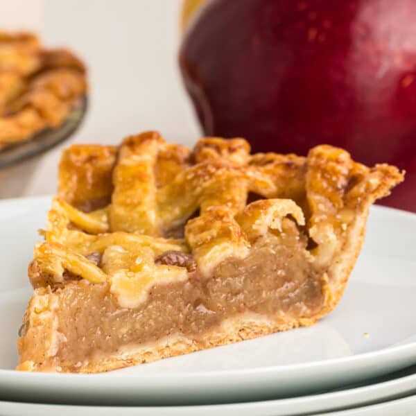 Close-up square photo of apple pie slice showing flaky crust and apple filling.