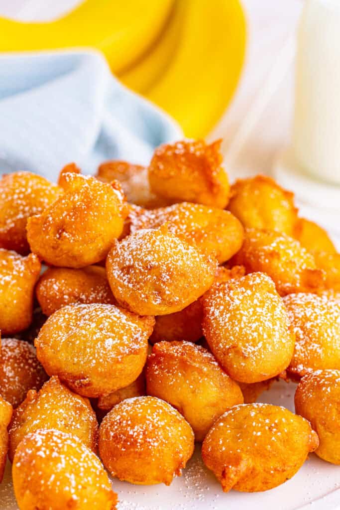 Close-up of golden, crispy banana fritters dusted with powdered sugar ready to serve
