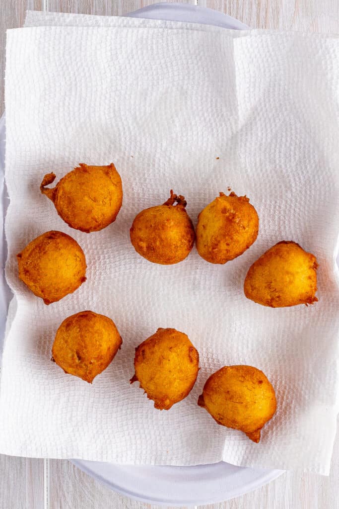 Freshly fried banana fritters draining on paper towels to remove excess oil