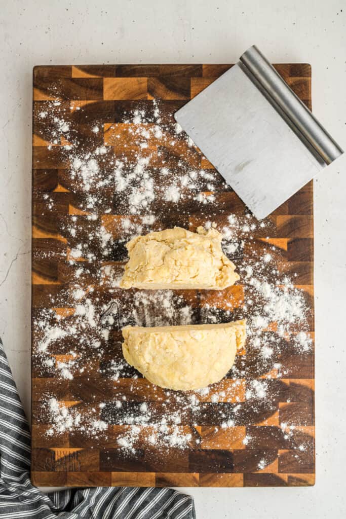 Butter pie crust dough cut in half on floured board, ready to shape