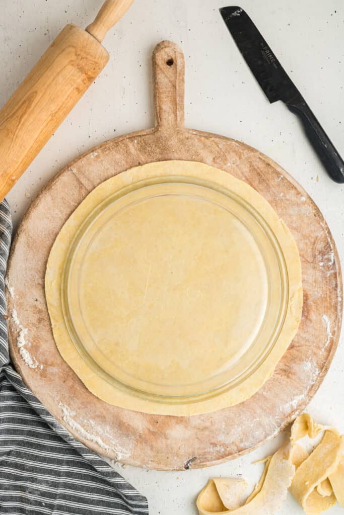 Rolled and trimmed pie crust perfectly shaped under a pie plate on floured board