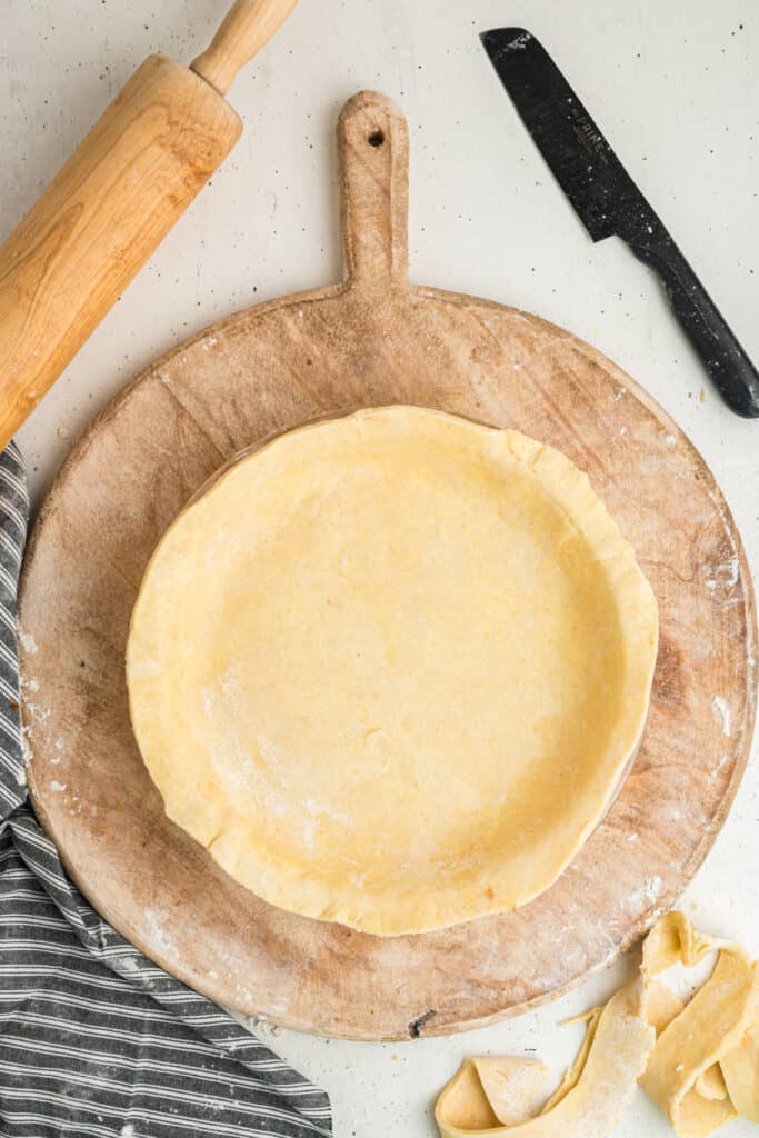 Unbaked pie dough pressed into a pie dish, ready for trimming and crimping