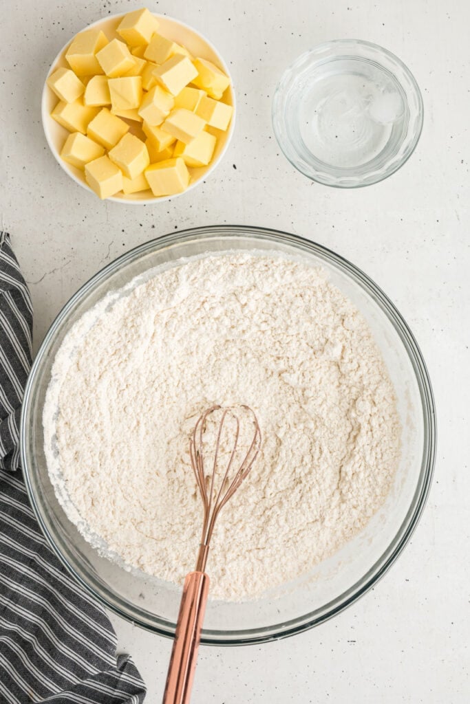 Whisk mixing dry ingredients in a large glass bowl for homemade pie crust