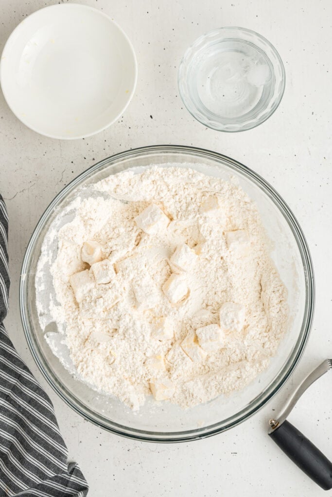 Butter cubes coated with flour in a mixing bowl for pie crust preparation