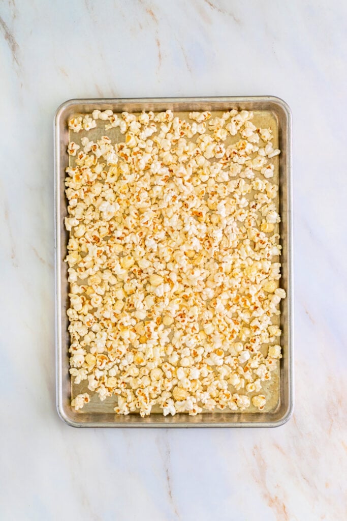 Baking sheet filled with plain popped popcorn ready for caramel coating