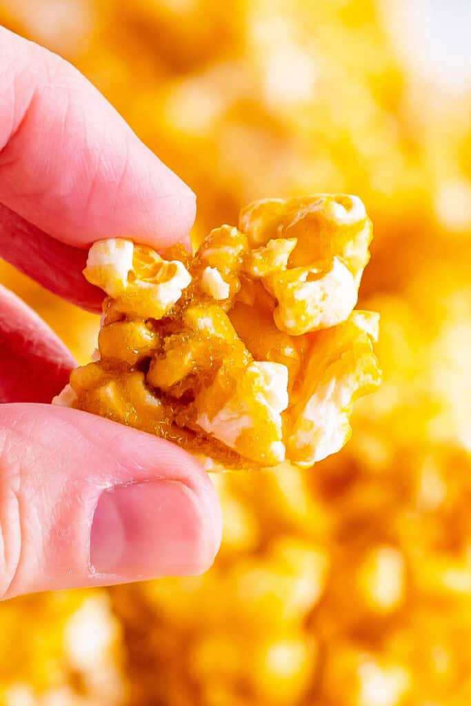 Close-up of fingers holding a cluster of crunchy caramel corn