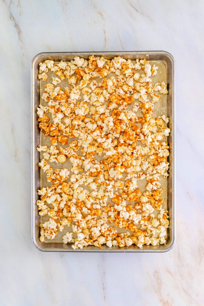 Baking sheet with partially coated popcorn in caramel before baking