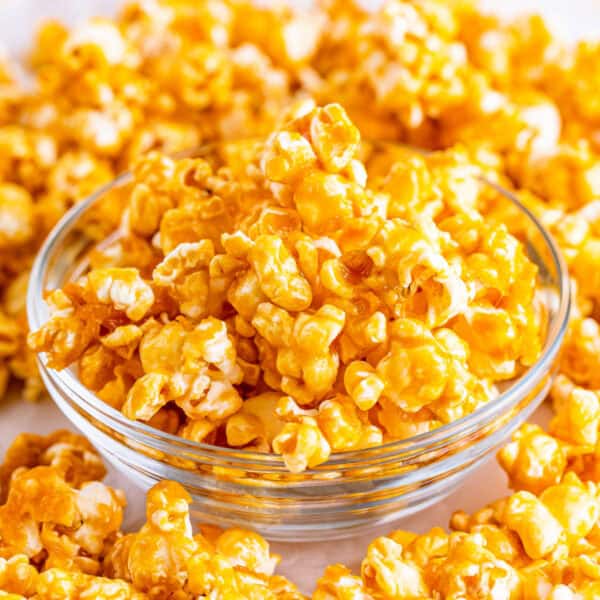 Square crop close-up of a glass bowl filled with golden caramel corn