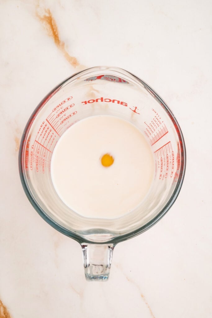 Milk, egg, and vanilla in a glass measuring cup before mixing