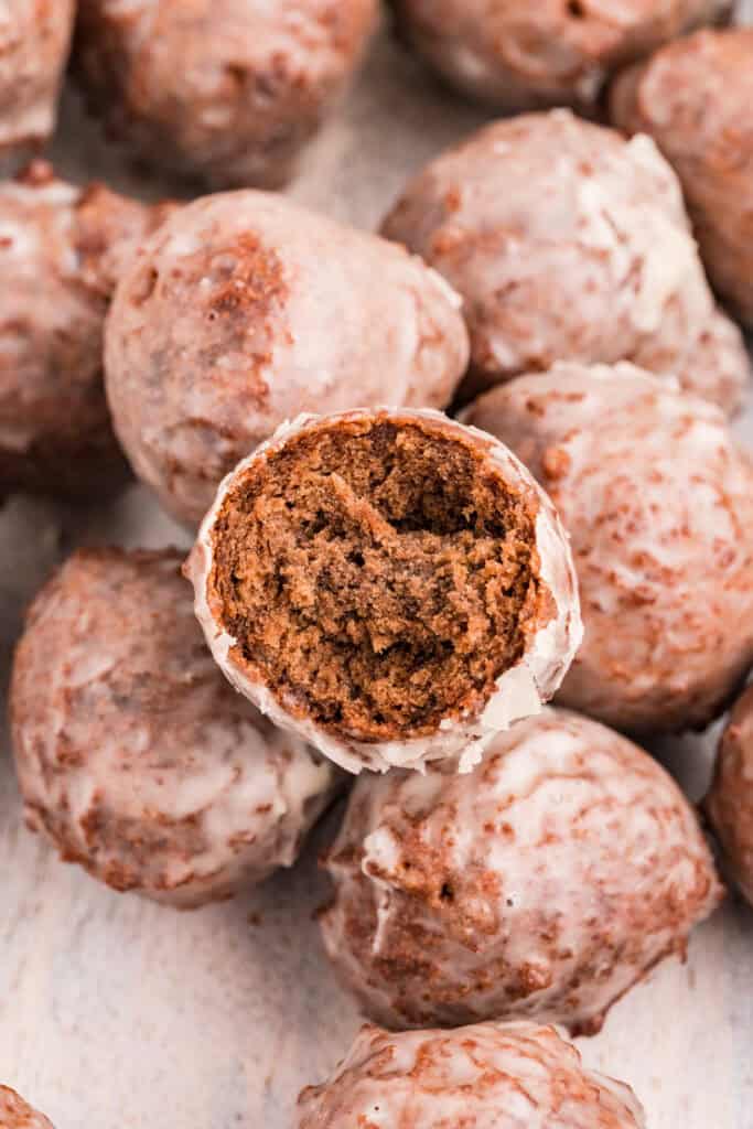 Overhead shot of glazed chocolate donut holes with one donut cut open