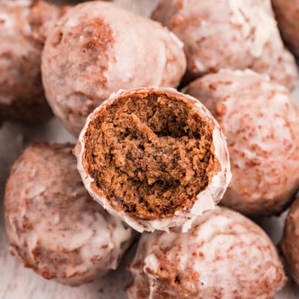 Square image of glazed chocolate donut holes with one cut open to show inside